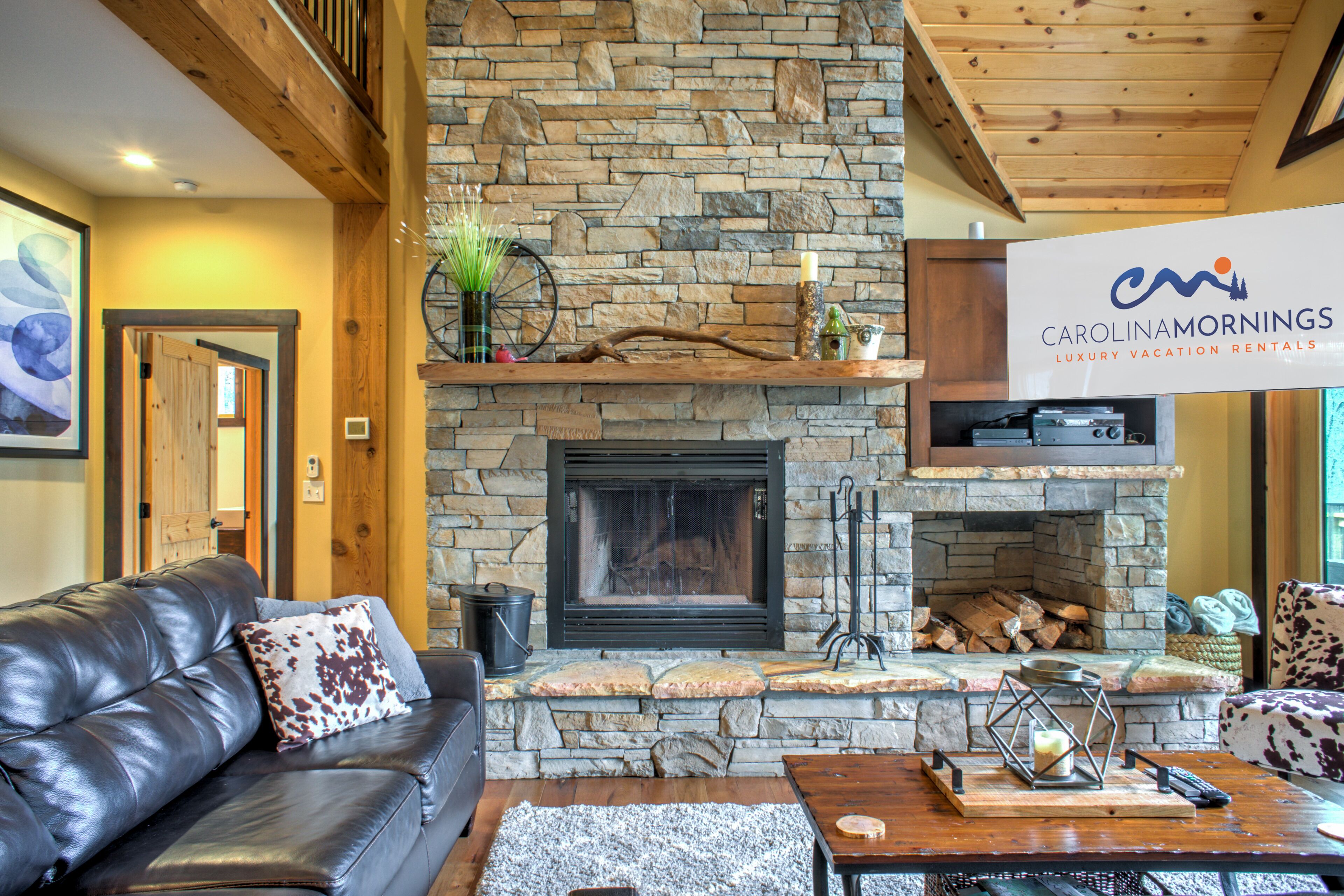 A cozy living room with a stone fireplace, a leather couch, and a wooden coffee table.