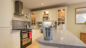 A modern kitchen with white cabinets, a built-in oven, a stainless steel range, and a granite countertop. - 2 Kings Yard (Sedbergh)