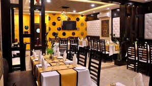 Un restaurante con varias mesas, cada una con manteles blancos y sillas de madera oscura.