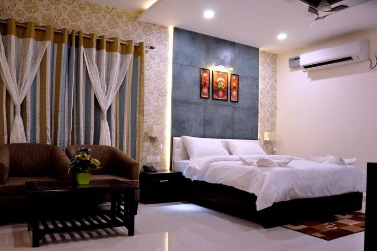 A bedroom with a bed, a sofa, a nightstand, and a wall-mounted air conditioner.