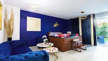 Een kamer met een blauwe bank, een houten receptiebalie en een kleine tafel met een ananas en bloemen.