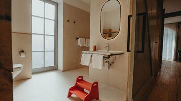 Un baño moderno con un ventanal grande, un lavamanos con dos toallas, un escalón rojo y un espejo.