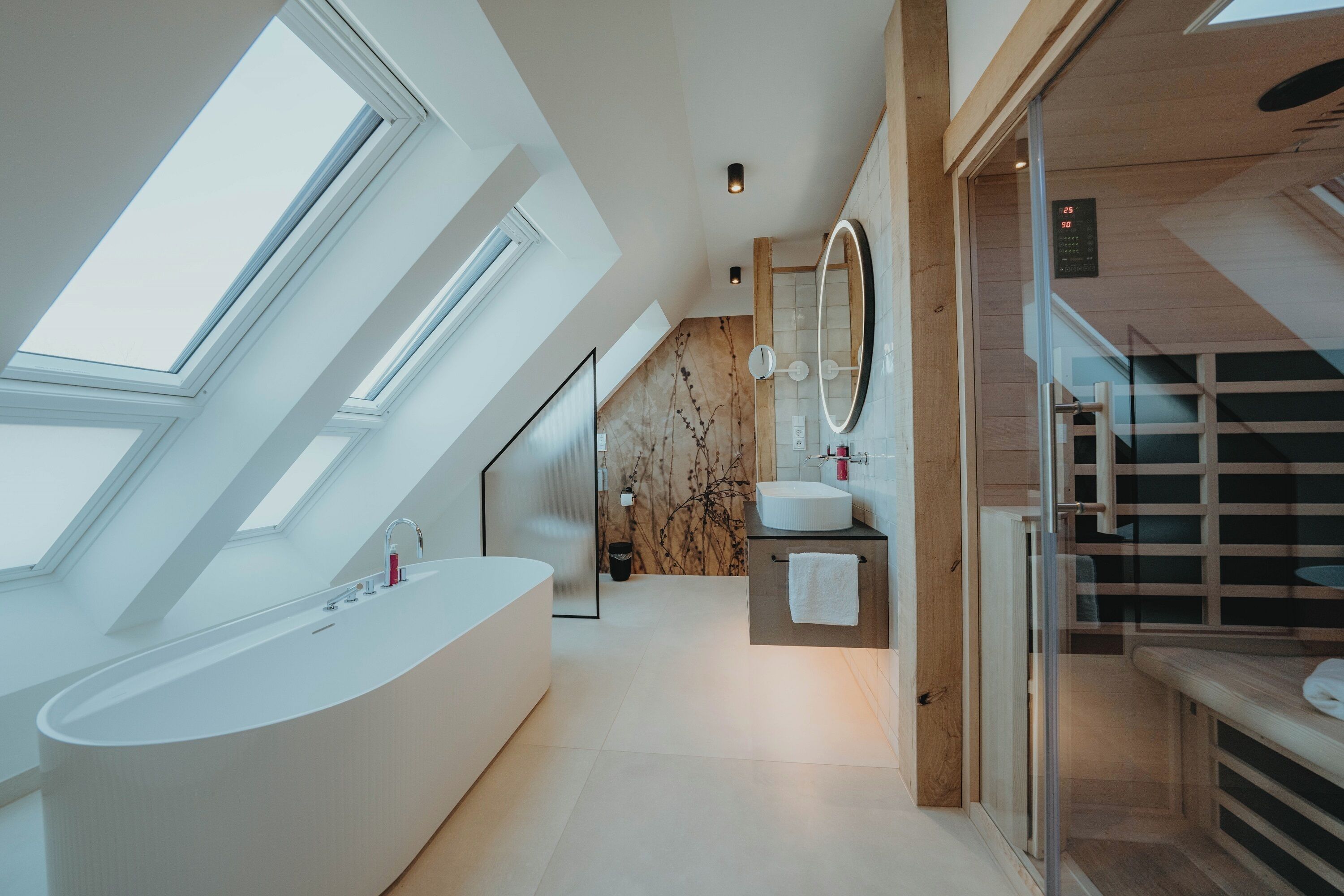 A modern bathroom with skylights, a freestanding bathtub, a vanity with a mirror, and a shower area.