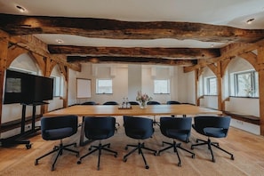 A conference room with a long table, six chairs, a TV, and wooden beams on the ceiling. - Wildland Natural Resort (Wietze)