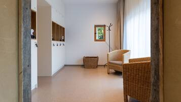A room with a wicker chair, a small window, and a coat rack.