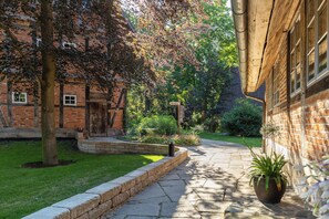 Un bâtiment en briques avec un chemin de pierre, un arbre et une plante en pot.