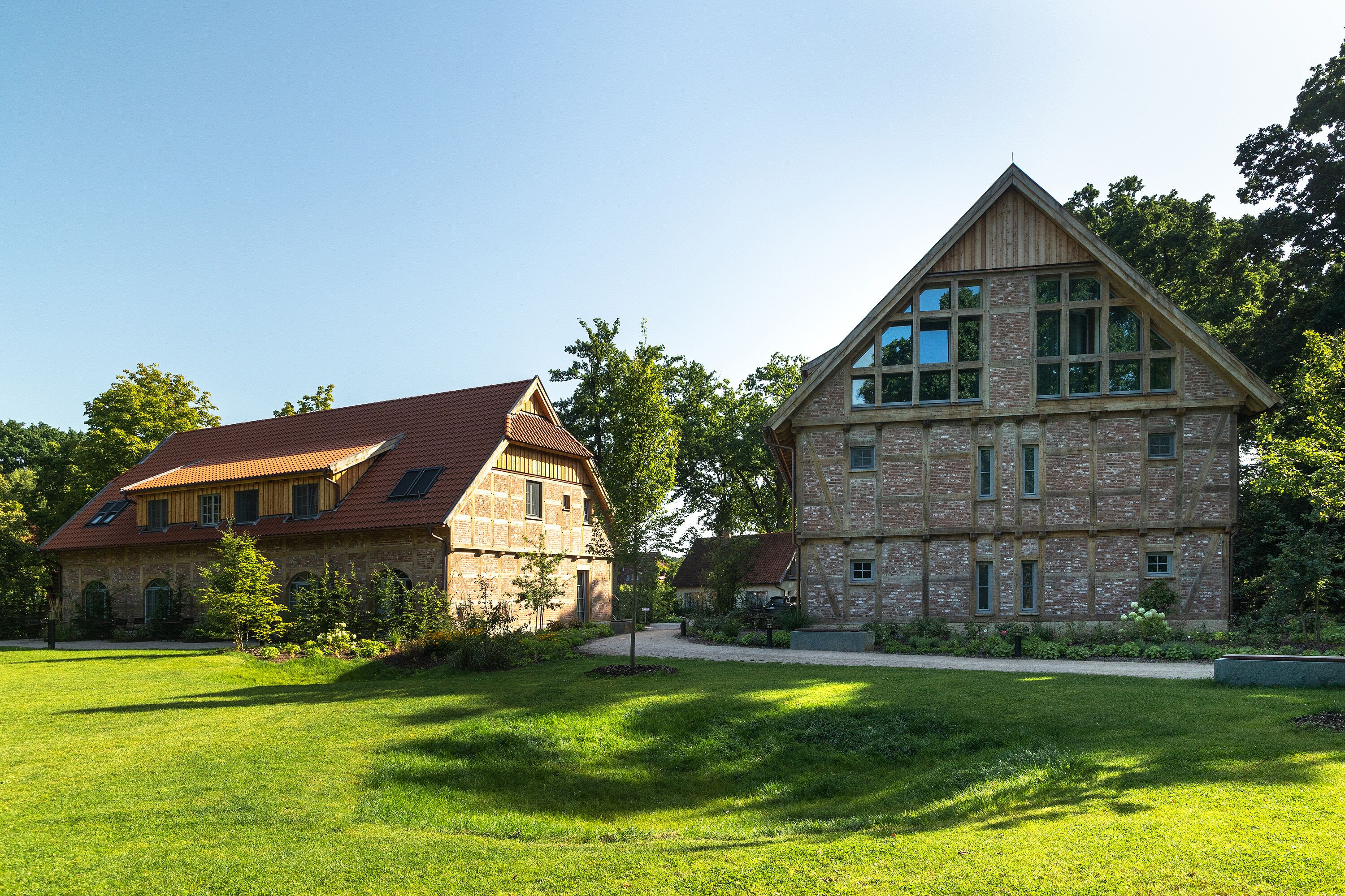 A large, two-story stone building with a red-tiled roof and multiple windows.