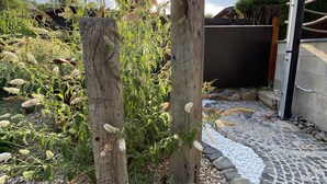 Un jardin agrémenté de poteaux en bois, de plantes et d’un chemin pavé de pierres.