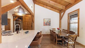 A spacious kitchen with a large island, wooden beams, and a dining area with a table and chairs.