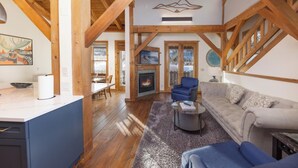 A spacious living area with a fireplace, wooden beams, and a view of the outdoors.