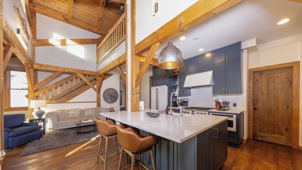 A spacious kitchen with a central island, wooden beams, and modern appliances.