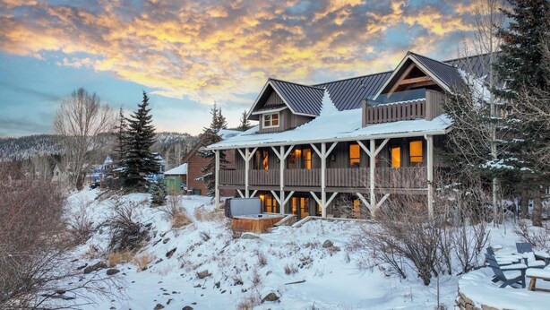 Un gran lodge de varios pisos con fachada de madera y varios balcones, rodeado por un paisaje nevado y árboles.