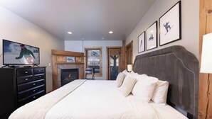 Un dormitorio con una cama grande, un televisor en una cómoda, una chimenea y cuadros en la pared.
