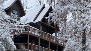 Una cabaña de madera con balcón y un paisaje cubierto de nieve.
