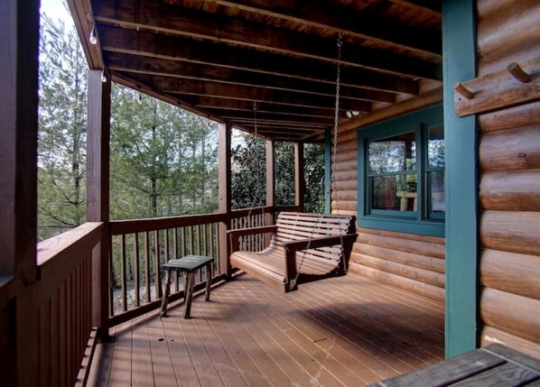 Une cabane en bois avec une véranda, un banc et une table.