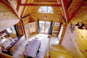 A wooden cabin with a dining area, a staircase, and a large window. - Escape to tranquility. Secluded, private and convenient. 2 miles from Gatlinburg (Gatlinburg)