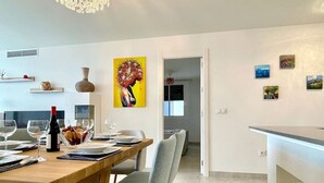 Un espace repas moderne avec une table en bois, des chaises grises et un comptoir blanc.