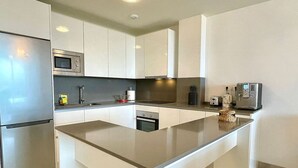 Une cuisine moderne dotée d’un îlot central, d’appareils électroménagers intégrés et d’un design minimaliste.