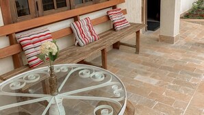 A cozy outdoor seating area with a round glass table, wooden bench, and striped cushions. - Pousada Capim Limão (Diamantina)