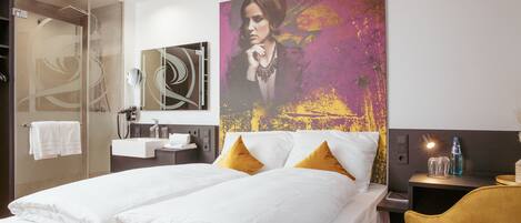 Una habitación de hotel con cama, un cuadro grande, un baño y un escritorio con silla.