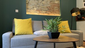 A modern living room with a grey sofa, yellow cushions, a round wooden coffee table, and a potted plant. - #CD L' Ainé 👨‍👩‍👦‍👦| Jean Jaurès | Tramway A, B and E| T3 équipé (Grenoble)