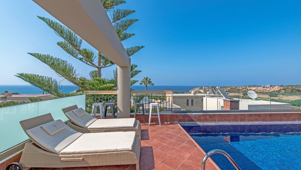 Un área de piscina en la azotea con sillones de descanso, una piscina pequeña y vistas al mar.