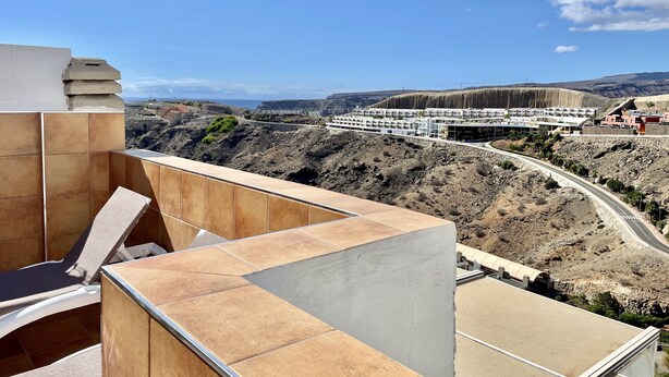 Terraço com vista para a paisagem costeira, incluindo uma estrada e edifícios.