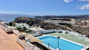 Piscina no terraço com vista clara do oceano e da paisagem rochosa ao redor.