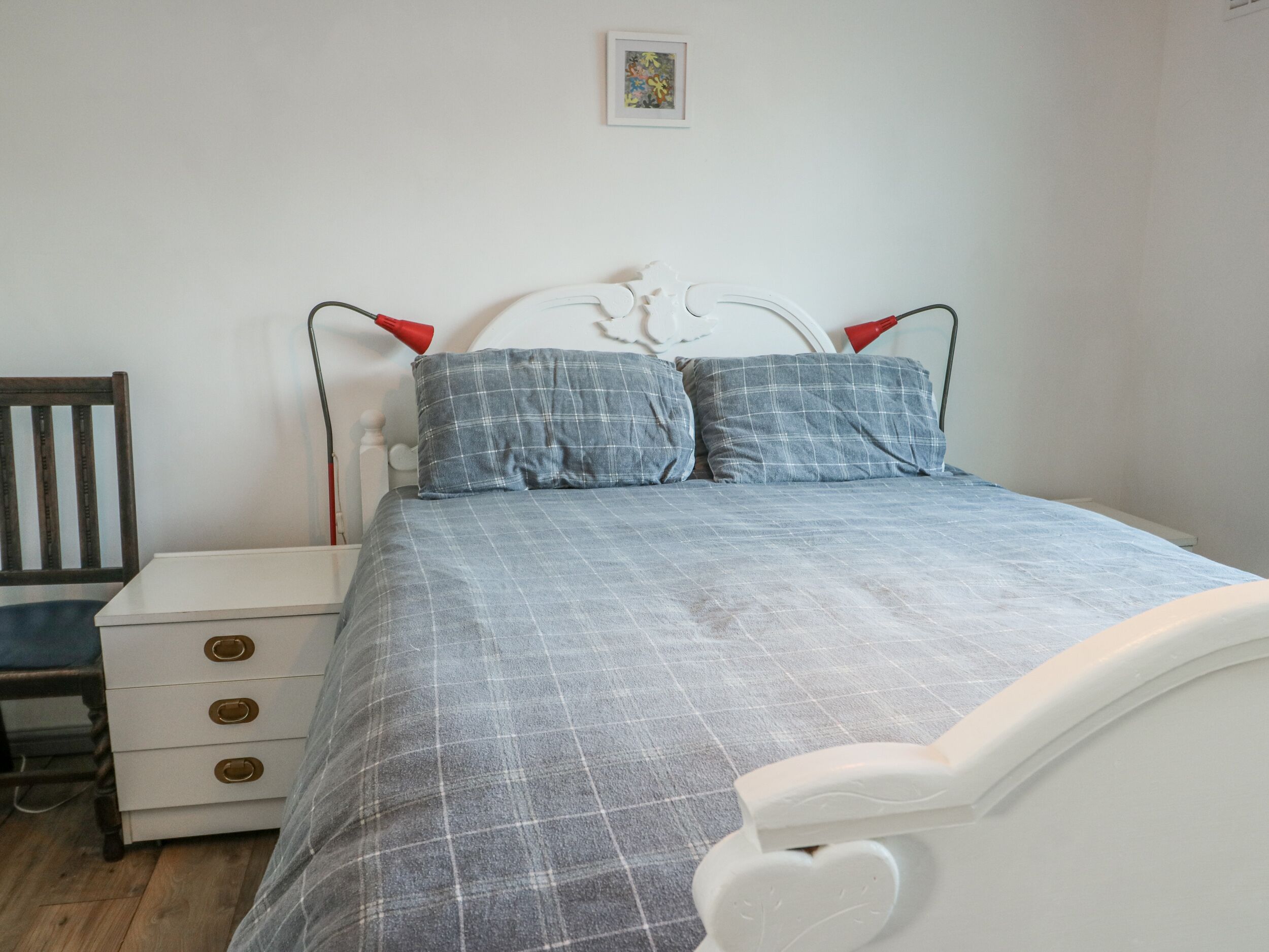 A bedroom with a bed, a nightstand, a chair, and a small table.