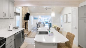 Een moderne keuken met een centraal eiland, witte kasten en een open haard.