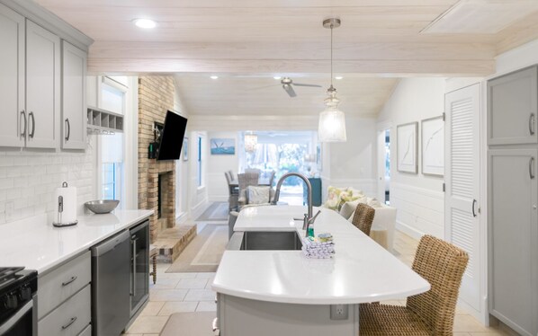 A modern kitchen with a central island, white cabinetry, and a fireplace.