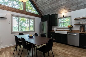 A modern kitchen with a wooden ceiling, black cabinets, a stainless steel refrigerator, and a wooden dining table with chairs. - Star View Cabin HOT TUB*Pets Ok*Long Range Views*K K Q 4TB (Deep Gap)