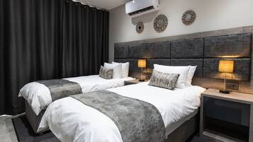 Een moderne hotelkamer met twee bedden, een groot raam, een airconditioning en decoratieve spiegelwanden.