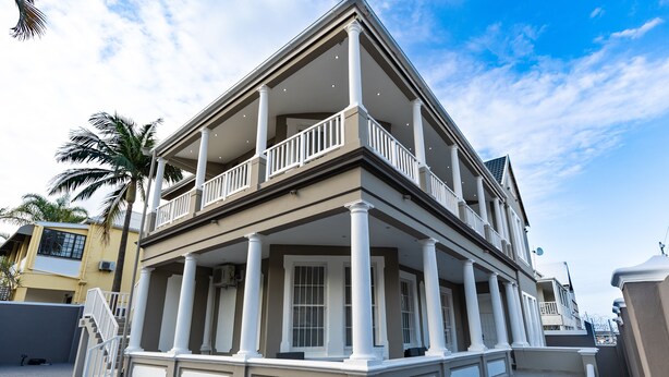 A two-story building with a balcony, columns, and a staircase leading to the entrance. - Luxe Suites Boutique Hotel (Durban)