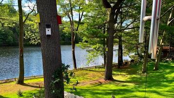 Un parc avec un lac, des arbres et une terrasse en bois.