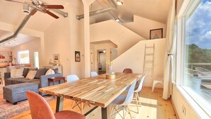 Un vaste espace de vie comprenant une table à manger en bois, des chaises modernes et une grande fenêtre donnant sur l’extérieur.