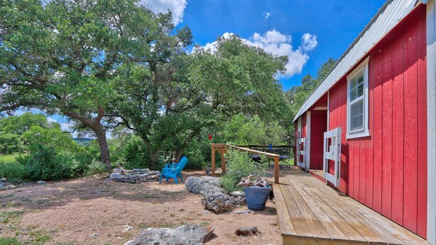 Un edificio in legno rosso con un patio di legno, circondato da alberi e rocce.