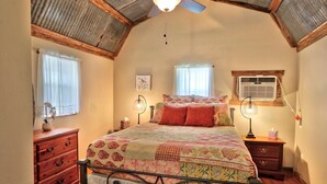 Una camera da letto con un letto, una cassettiera in legno, lampade da comodino e una ventola a soffitto.