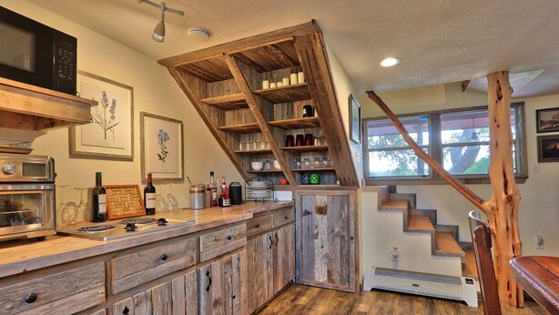 Eine Küche mit Holzausbau, einer eingebauten Mikrowelle und einer Holztreppe.
