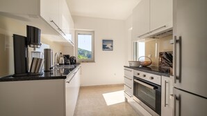 A modern kitchen with stainless steel appliances, white cabinetry, and a view of the outdoors through a window. - Villa Sabine Medveja Cres. Studio-appartement mit Wlan und Pool (Medveja)