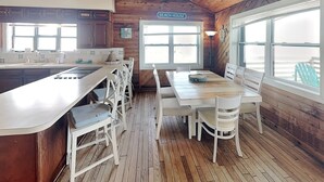 A beach house interior with a kitchen, dining area, and large windows offering views of the beach. - Dreamview by Distinctive Beach Rentals (St. Augustine)