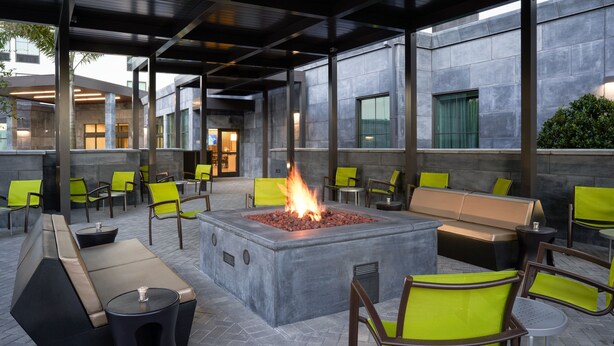 An outdoor seating area with a fire feature, cushioned benches, and chairs.