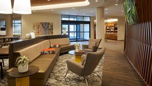 A modern lobby with a curved sofa, armchairs, a coffee table, and a large screen wall.