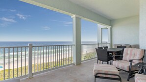 Un espace extérieur abrité avec vue sur la plage et l’océan. On y trouve des chaises et une table.