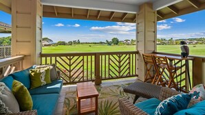 A covered outdoor seating area with a view of a golf course.