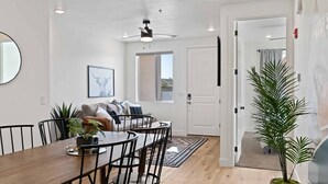 En matplats med ett träbord och stolar, en takfläkt och en stor spegel på väggen.