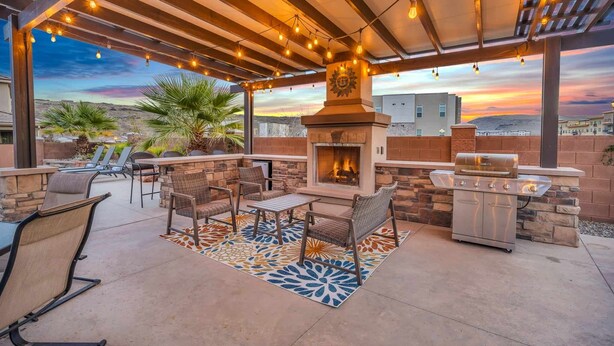 An outdoor patio with a stone fireplace, grilling station, and seating area. - Zion Reunion Poolhouse, PRIVATE POOL, SLEEPS 24! (Washington)
