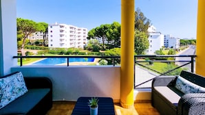 A balcony with a view of a swimming pool, a small table with a plant, and two sofas. - FLH Vilamoura Balcony with Pool (Vilamoura)