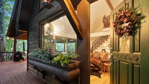 Una cabaña de madera con terraza, un jardín vertical incorporado con plantas, una escalera y una corona en la puerta.