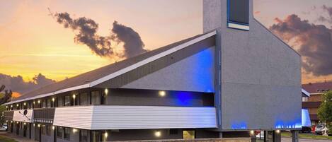 A modern hotel with a stone facade, multiple windows, and a flat roof.